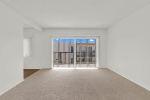 the living room of an empty apartment with a balcony at Copa Ladeene Apartments, Torrance California