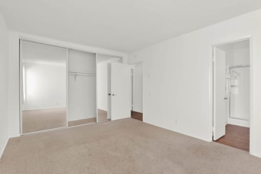 an empty living room with mirrored closet doors and carpet at Copa Ladeene Apartments, Torrance, CA