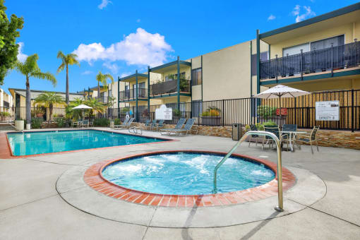our apartments have a swimming pool and a patio with chairs and umbrellas at Copa Triana Apartments, Torrance California
