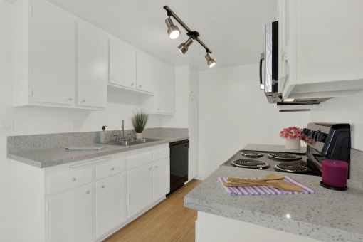a kitchen with granite counter tops and white cabinets at Copa Triana Apartments, Torrance, 90505