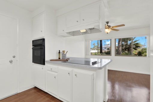a kitchen with white cabinets and a counter top and a black refrigerator  at Royal Towers Apartments, Redondo Beach, 90277