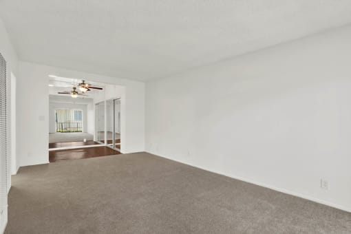 an empty living room with white walls and a ceiling fan at Olive Tree Apartments, Torrance