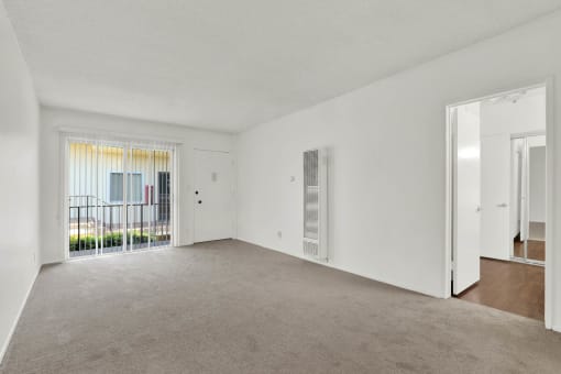 an empty living room with a door to a balcony at Olive Tree Apartments, Torrance California