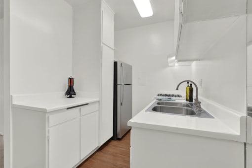 a kitchen with white cabinets and a sink and a refrigerator at Olive Tree Apartments, Torrance California