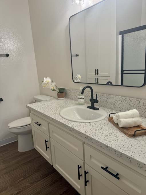 A bathroom with a white toilet and a sink with a black faucet. at Camino de Oro Apartments, Torrance, CA, 90505