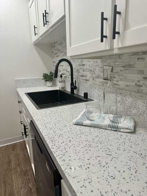 A kitchen with a black sink and a white speckled countertop. at Camino de Oro Apartments, Torrance, CA, 90505