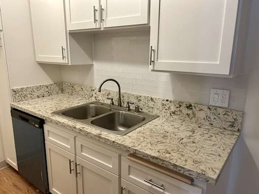 A kitchen with a marble countertop and white cabinets.
