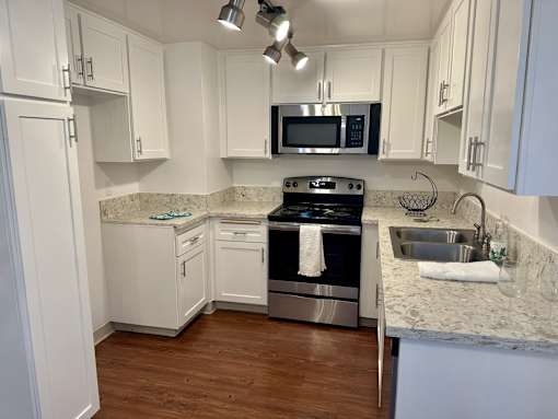 A kitchen with white cabinets and a black microwave above the stove.