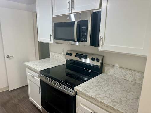 A kitchen with black appliances and white cabinets. at Copa Triana Apartments, Torrance