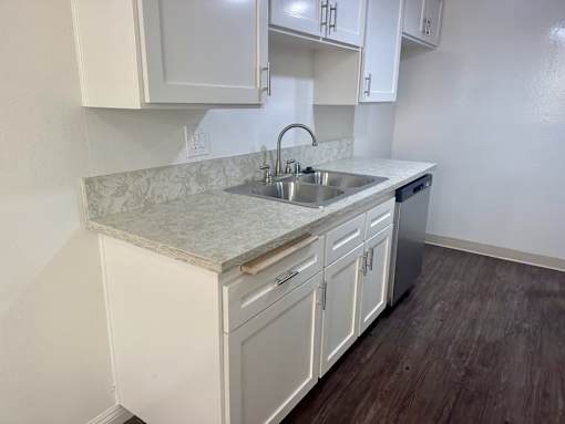 A kitchen with white cabinets and a marble countertop. at Copa Triana Apartments, Torrance