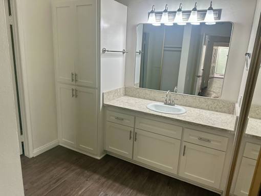A bathroom with a sink, mirror, and cabinets. at Copa Triana Apartments, Torrance