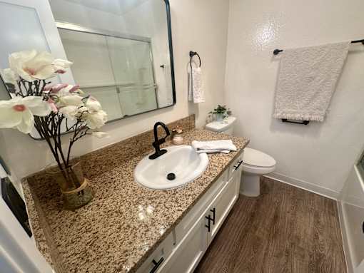 A bathroom with a granite countertop and a white sink at Willow Tree Apartments, California, 90505
