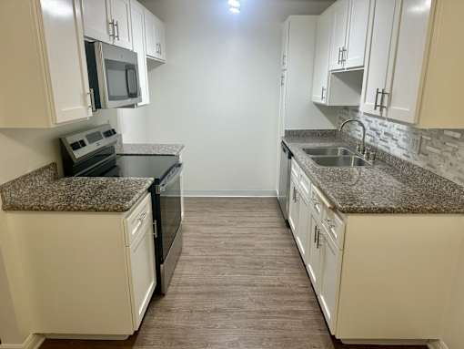 A kitchen with granite countertops and white cabinets.