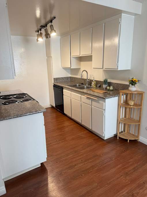 A kitchen with white cabinets and a wooden floor.