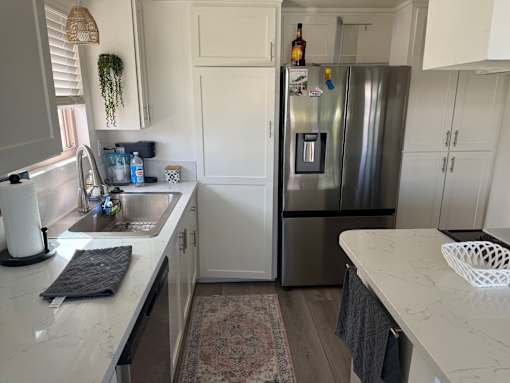 A kitchen with a refrigerator, sink, and cabinets.