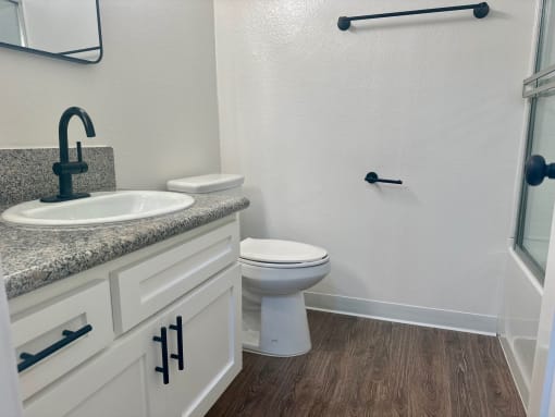 a bathroom with a toilet and a sink and a shower at Copa Ladeene Apartments, Torrance California