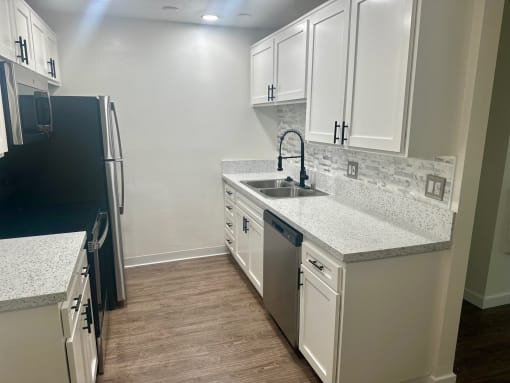 a kitchen with white cabinets and stainless steel appliances at Copa Ladeene Apartments, Torrance California