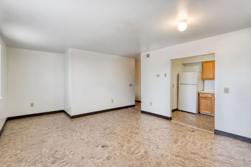 the living room and kitchen of an empty apartment with white walls and flooring