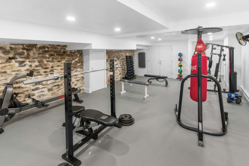 a gym with weights and other equipment and a stone wall