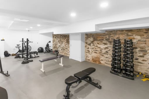 a workout room with weights and a stone wall