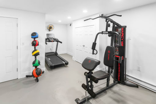 a gym with weights and cardio equipment in a home with white walls