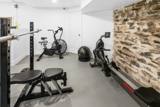 a gym with exercise equipment and a stone wall