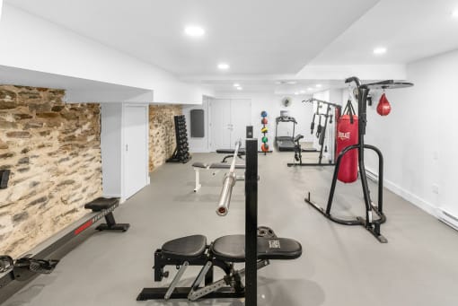 a gym with weights and other equipment and a stone wall