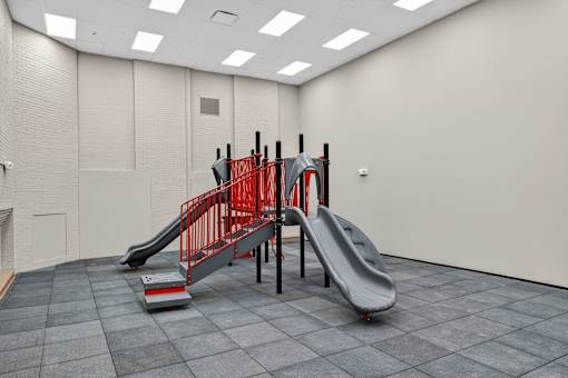 A red slide in a grey room.