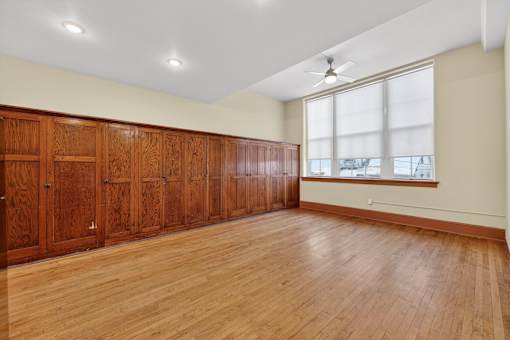 A room with wooden floors and a row of wooden cupboards.