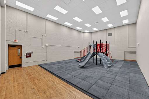 A gym with a slide and a wooden floor.