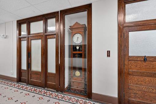 A clock is on a wooden stand in a room.