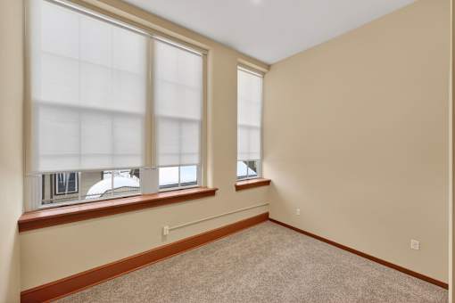 A room with two windows and carpeted floor.
