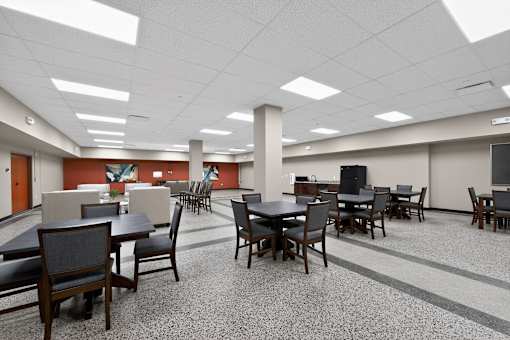 A room with tables and chairs and a television.