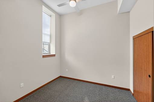 A room with a ceiling fan and a door.