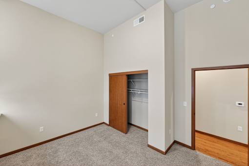 A room with a carpeted floor and a wooden door leading to a laundry room.