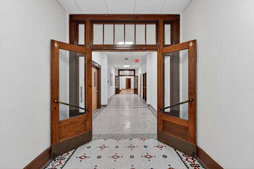 A hallway with a tiled floor and a row of doors on either side.