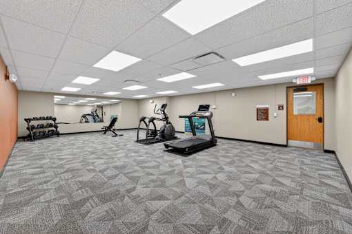 A spacious gym with treadmills, exercise bikes, and other equipment.