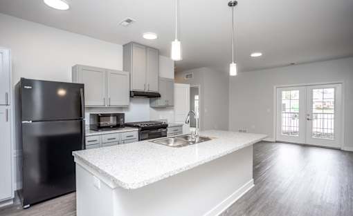 A modern kitchen with a black refrigerator and white countertops.