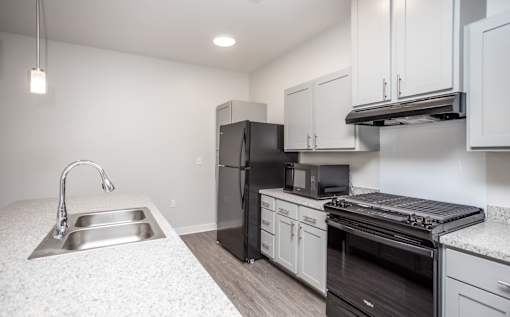A kitchen with a sink, refrigerator, oven, and microwave.