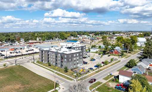 A view of a town with apartment buildings, cars, and trees.