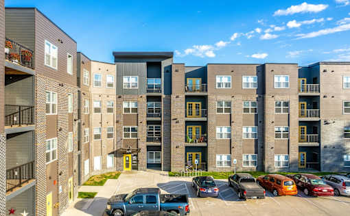A parking lot with cars and apartment buildings.