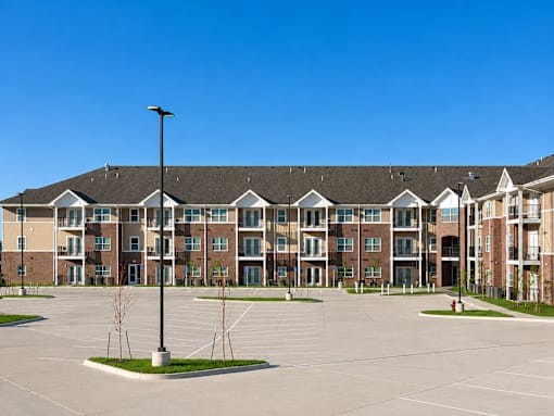 A large apartment complex with a parking lot in front.