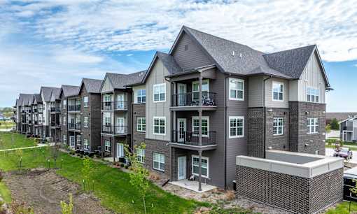 A row of modern townhouses with balconies and front yards.