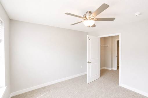 A room with a ceiling fan and carpeted floor.