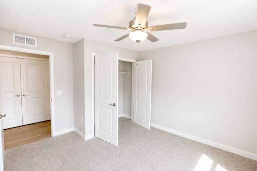 A room with a ceiling fan and two doors.