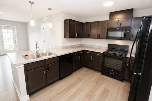 A kitchen with black appliances and brown cabinets.