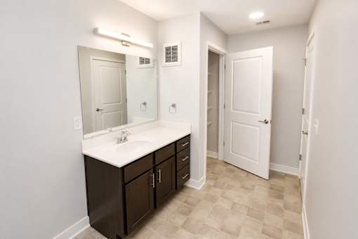 A bathroom with a sink, mirror, and cabinets.