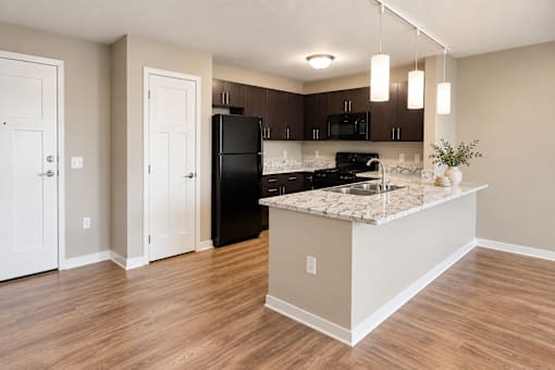 A kitchen with a black refrigerator and a marble countertop.