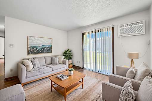 A living room with a grey couch, a wooden coffee table, and a painting on the wall.