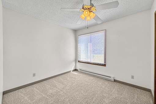 A room with a ceiling fan and a window with blinds.